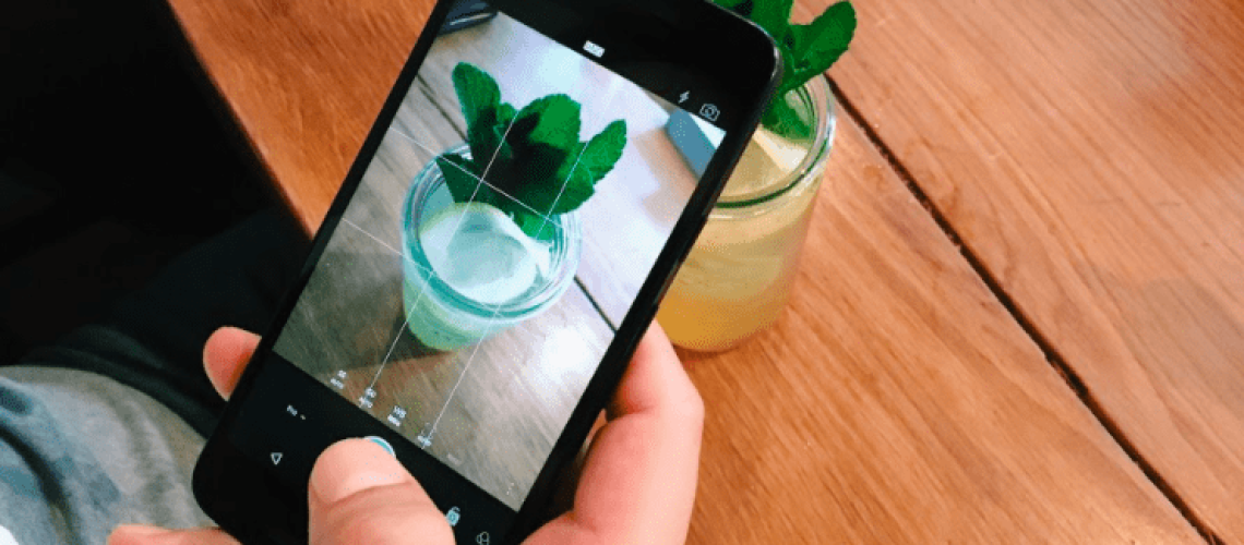 person taking a photo of their drink with an iphone