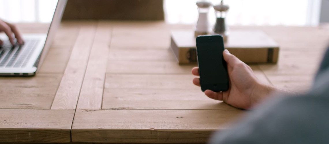 A display of smartphone technology device and laptop on a wooden table. Original public domain image from Wikimedia Commons